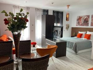 una sala de estar con una cama y una mesa con un jarrón de flores en Apartamentos "El Escondite de Triana" en Sevilla