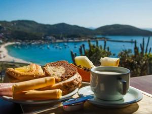 a table with a plate of bread and a cup of coffee at Pousada Tanto Mar in Arraial do Cabo