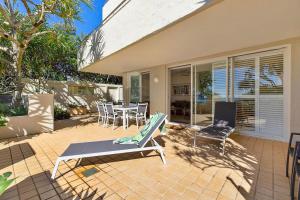 una casa con patio arredato con sedie e tavolo di Portofino 1 - Beachfront Apartment Noosa Heads a Noosa Heads
