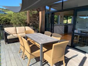 un patio con mesa y sillas en una terraza en The Cottage at Te Whau Retreat en Te Whau Bay