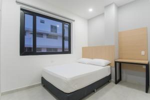 a bedroom with a bed and a desk and a window at Stanza Hotel Sincelejo in Sincelejo