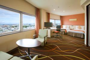 um quarto de hotel com duas camas e uma mesa e cadeiras em Okinawa NaHaNa Hotel & Spa em Naha