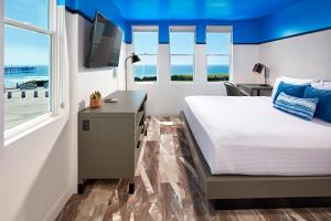 a bedroom with a bed and a desk with a television at Pacific View Inn in San Diego