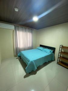 a bedroom with a blue bed in a room at Cabinas El Paso de Moisés in Uvita