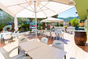 un patio con mesas, sillas y una sombrilla en Hotel Rural Serrella en Castell de Castells