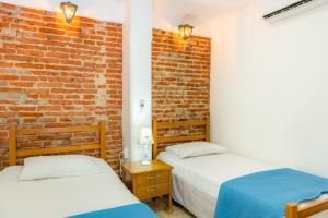 dwa łóżka w pokoju z ceglaną ścianą w obiekcie Casa Caribe Colonial w mieście Barranquilla