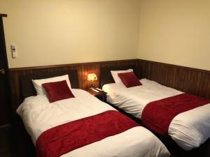 two beds in a hotel room with red and white sheets at 露伴ロハンrohan in Oshima
