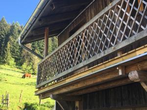 a wooden building with a horse grazing in a field at Ferme des Moines in Pontarlier