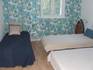 two beds in a room with blue and white wallpaper at Gîte les Hortensias in Beauquesne