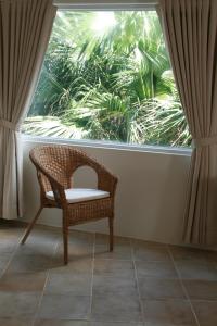 een rieten stoel voor een groot raam bij Seashore My Home in Eluan