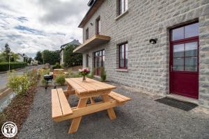 a wooden picnic table in front of a brick building at Gîte de Granit Bleu in Besse-et-Saint-Anastaise