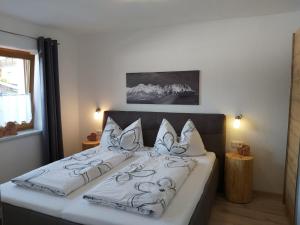 una camera da letto con un grande letto con cuscini bianchi di Ferienwohnung Innerbichler a Ellmau