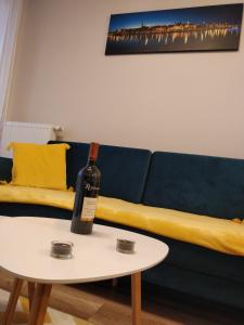 - une bouteille de vin assise sur une table à côté d'un canapé dans l'établissement Apartament Cukrownia, à Szczecin