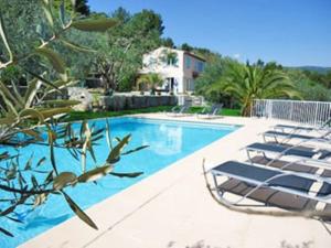 a swimming pool with lounge chairs next to a house at Villa la Grette in Fayence