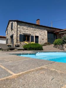 a stone house with a swimming pool in front of it at Domaine des Pierres D Auvergne in Flat