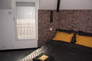 łóżko z żółtymi poduszkami i ceglaną ścianą w obiekcie Meublé de tourisme 3 étoiles Loft industriel à Fismes w mieście Fismes