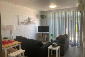 a living room with a couch and a tv at Walk to Lamberts Beach with Wi-fi and Netflix in Slade Point