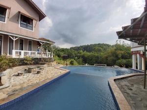a swimming pool in front of a building with a house at Degung Hillside in Bogor