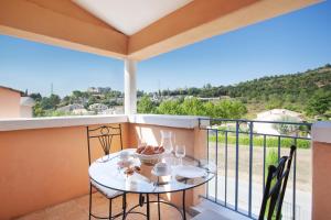 a balcony with a table and a view of a hill at Résidence Odalys La Licorne de Haute Provence in Gréoux-les-Bains