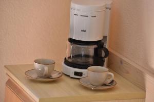 una macchinetta del caffè e due tazze su un bancone di APPARTAMENTI SAN GIOVANNI a Livigno