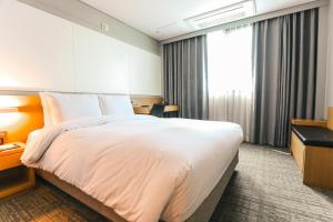 um quarto de hotel com uma cama grande e uma janela em ON City Hotel em Cheonan