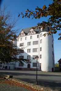 un bâtiment blanc avec une tour sur le côté d'une rue dans l'établissement Pension Schloss Heringen, à Heringen