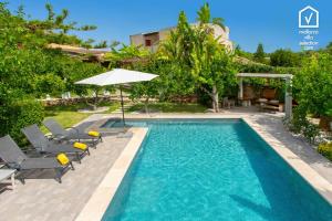 a swimming pool with chairs and an umbrella next to a house at Finca MARIPOSA Alcudia in Alcudia