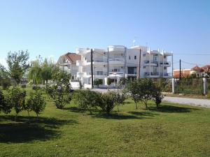 un gran edificio blanco con árboles delante de él en Crystal Aura, en Paralia Katerinis