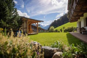 a house with a grassy yard with a building at Haus Gletscherblick in Neustift im Stubaital
