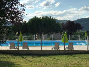 un gruppo di sedie e ombrelloni accanto alla piscina di Camping Le Mondou a Saint-Julien-de-Lampon