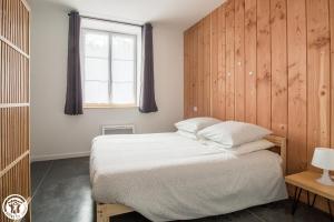 a bedroom with a bed with a wooden wall at Gîte de Granit ROSE in Besse-et-Saint-Anastaise
