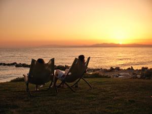 a couple sitting in chairs watching the sunset at Cavo Orient Beach Hotel & Suites in Tragaki