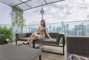 a woman sitting on a bench on a balcony at Ceylonz Suites KL Tower by KL HomeStay in Kuala Lumpur