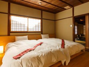 a bedroom with a large white bed with a red scarf on it at Tawara-an in Kyoto