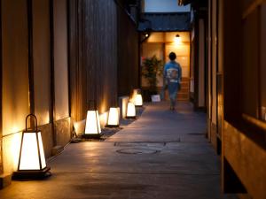 a person walking down a hallway with lights on it at Tawara-an in Kyoto
