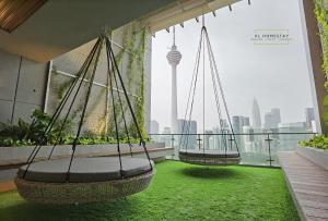 two swings on a balcony with a view of the city at Ceylonz Suites KL Tower by KL HomeStay in Kuala Lumpur
