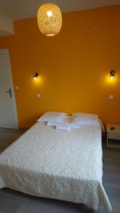 - une chambre avec un lit blanc et un mur orange dans l'établissement CAFE DE PARIS, à Lesparre-Médoc