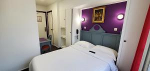 a small bedroom with a white bed and purple walls at Metropol in Paris
