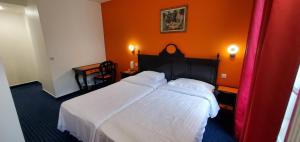 a bedroom with a white bed with an orange wall at Metropol in Paris