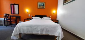 a bedroom with a white bed with an orange wall at Metropol in Paris