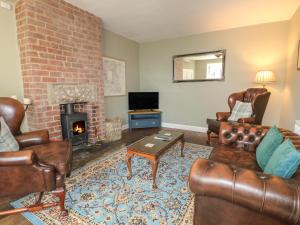 a living room with leather furniture and a fireplace at Holmefield in Bakewell