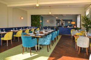 um restaurante com mesas e cadeiras azuis e amarelas em Kingscliff Hotel em Clacton-on-Sea