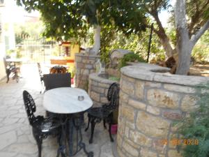 una mesa y sillas junto a una pared de piedra en Melios Rooms, en Petalidi