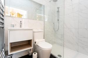 a white bathroom with a shower and a toilet at Stay Coastal in Whitley Bay