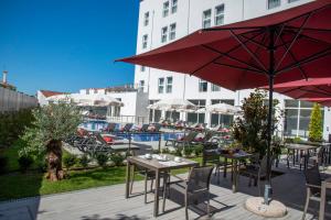 um ptio com mesas e guarda-sis ao lado de uma piscina em Luna Hotel de Tbua na Tbua