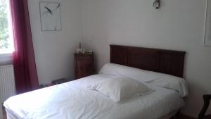 ein Bett mit weißer Bettwäsche und einem Kopfteil aus Holz im Schlafzimmer in der Unterkunft chez sylvette in Quinsac