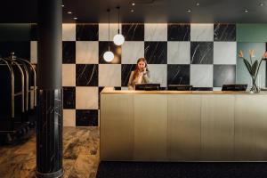 a woman talking on a phone at a reception desk at Townhouse Stadt Hamburg Wismar in Wismar