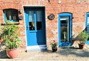 a blue door and two potted plants in front of a brick building at -Klärchen- die gemütliche 2P Ferienwohnung in Gedelitz, Wendland Elbe in Trebel