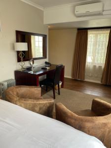 a hotel room with a bed and a desk and chairs at Cotswold House in Cape Town