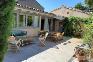 a patio with a table and chairs and a couch at Loft atelier dans ancien domaine viticole in Moux